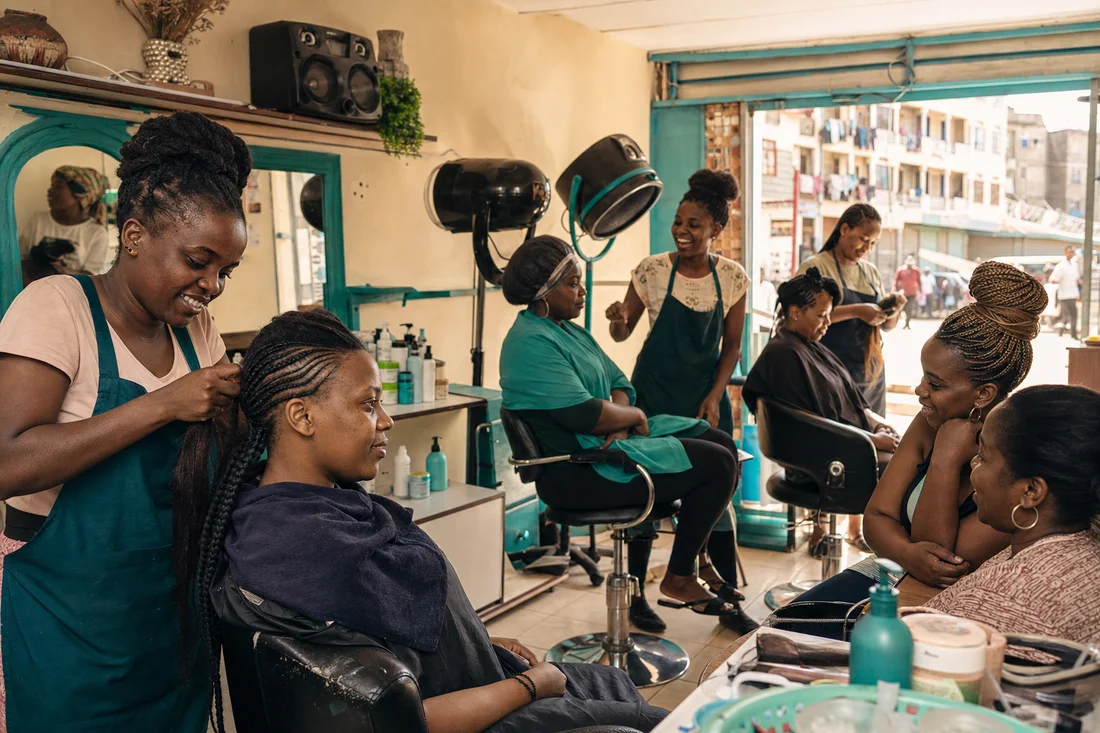 Busy Saturday morning inside Neema Glow Salon and Spa in Umoja Estate with stylists, mirrors, and hair dryers